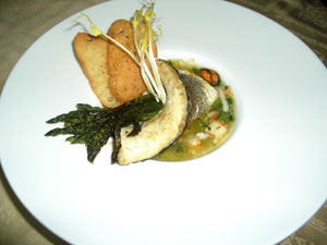 La cornucopia di branzino con fascetto di asparagi selvatici in guazzetto di mare e fettine di pane fritto